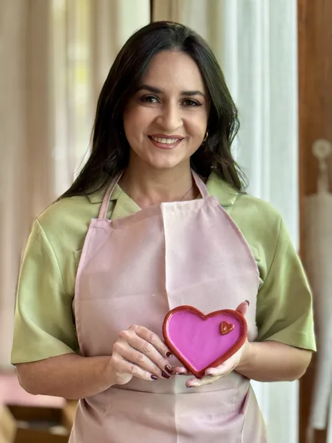Participante de avental rosa segura uma peça em forma de coração.