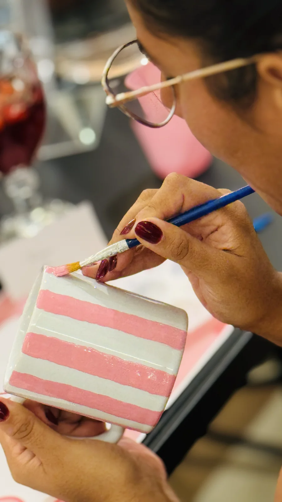 Participante pinta listras rosa em uma caneca.