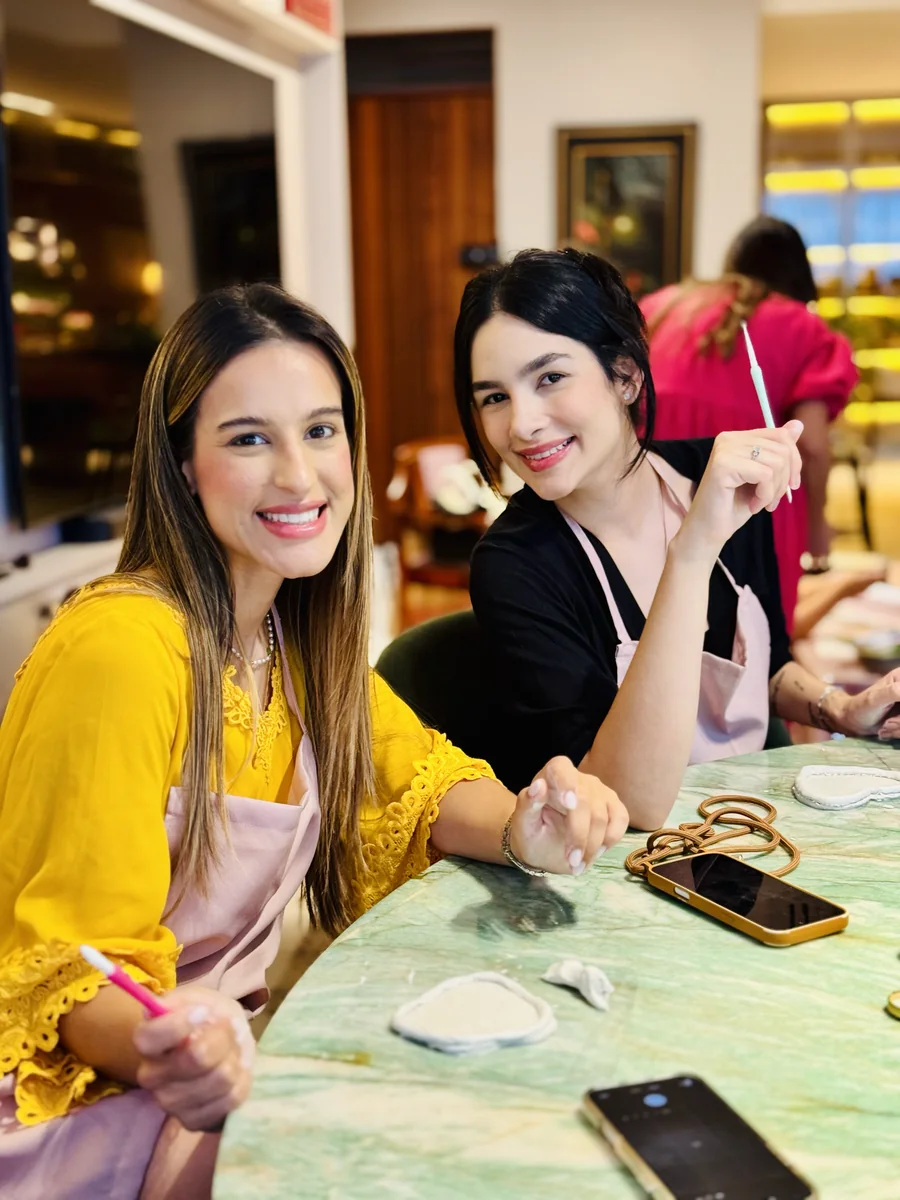 Duas participantes criam juntas à mesa de uma oficina.
